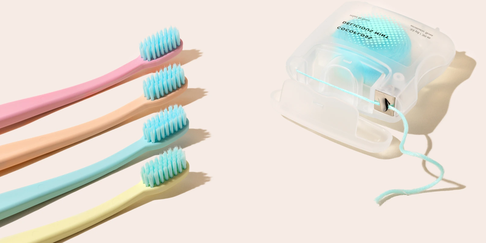 Cocofloss dental floss and colorful toothbrushes on a warm blush background